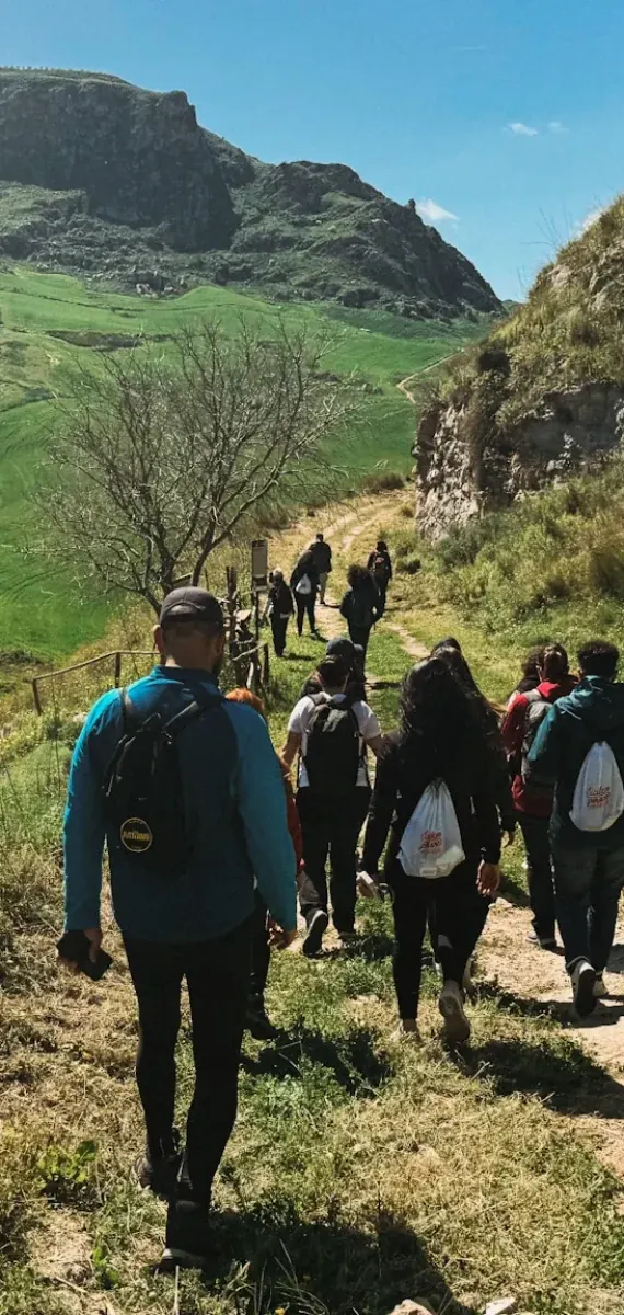 Un gruppo in cammino su un sentiero verde, visto da dietro, dall’archivio Val di Kam.